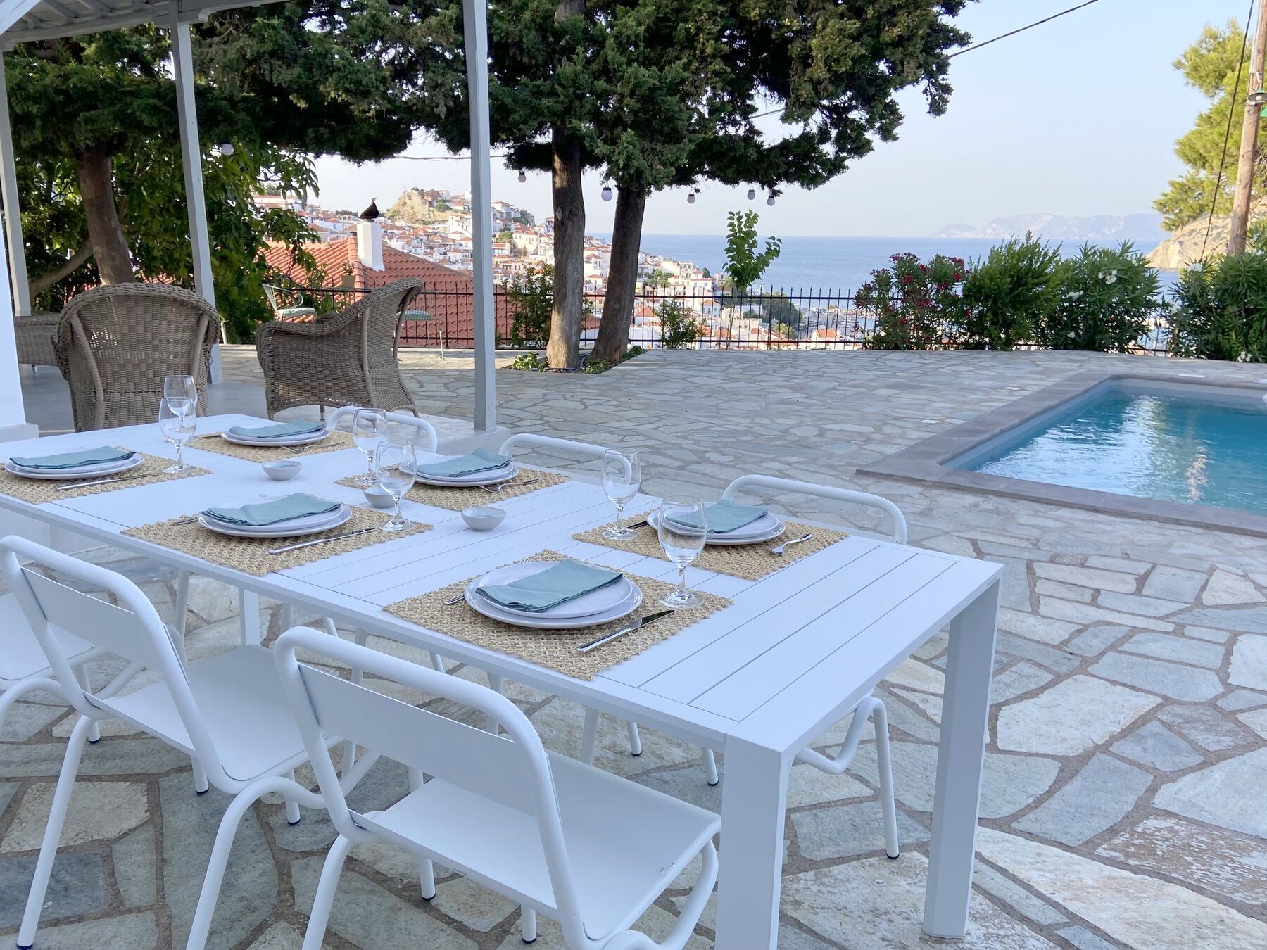 The outdoor table set for dinner, with the pool and the town beyond