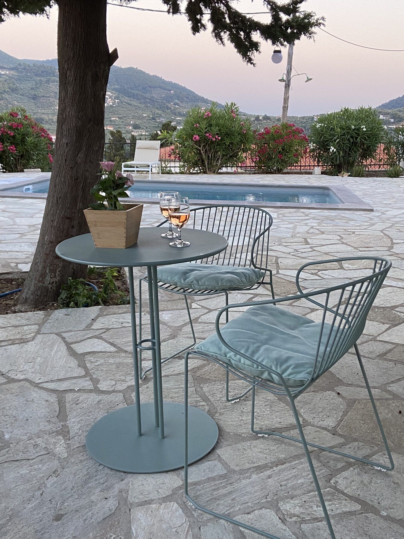 A table set with wine beside the pool at Villa Icelle, hills behind